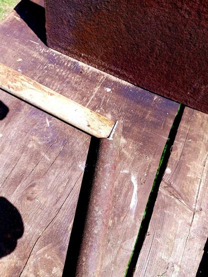 Two metal pipes in various states of rustyiness, laid together at an angle. Where they join, one has been cut to match the other. One part is has fresh metal ground for welding.