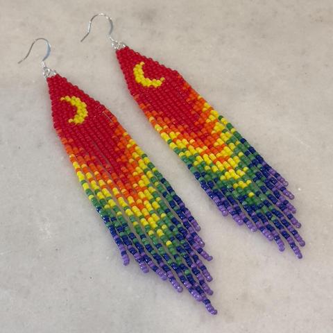 A pair of beaded fringe earrings in the rainbow pride colors with a yellow crescent moon shape on the brick stitch top