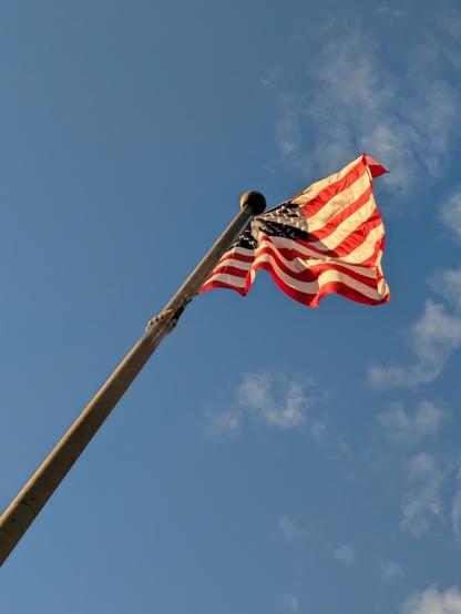 The American flag flies above Freedom Plaza in Washington, D.C., in the fall of 2024, with a mostly clear blue sky above.