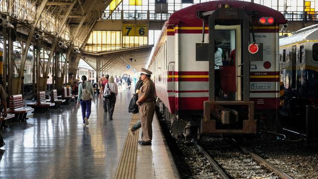 color photo in landscape format of a stationed tail end of a passenger train at a platform as passengers boarding the train