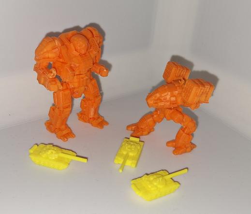 2 bright orange mechs stand facing each other, worth three yellow tanks at their feet