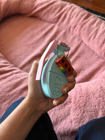 3D printed hand grenade shaped like Teva estradiol with a rainbow painted brick as the ring on the pin.