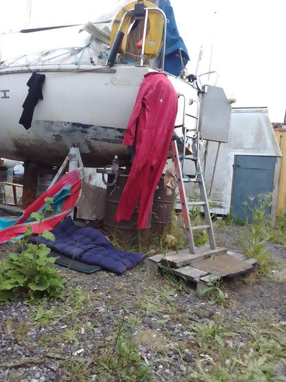 A red boiler suit hanging from the stern of a small yacht