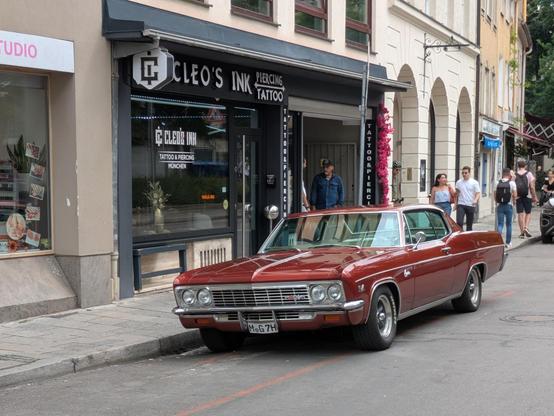 A Cadillac parked in front of a barber shop in Munich.