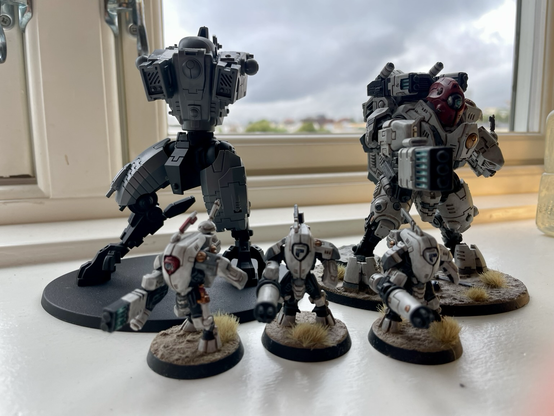 A team of stealth battlesuits in front of a ghostkeel and a riptide. The stealths and the ghostkeel are finished, while the riptide is not painted and lacks head and arms.