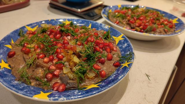 It's a dish of stew, topped with dill, pomegranate seeds, and fried onion, making it tantalisingly colourful