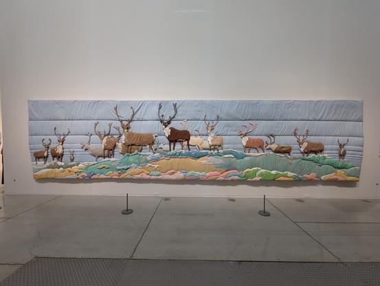 Quilted artwork that originally hung at #TTC #Spadina stations Kendal Avenue subway entrance entitled Barren Ground Caribou, 1977-1978

First time it's been exhibited outside the station. Shows a herd of caribou in a field with a light blue background
