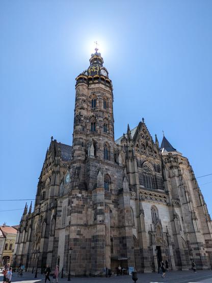 A large stone cathedral with the sun behind the tower