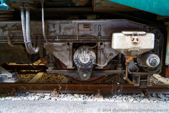 A close up detail photo of a wheel with it's engine and sand canister of an electric train.