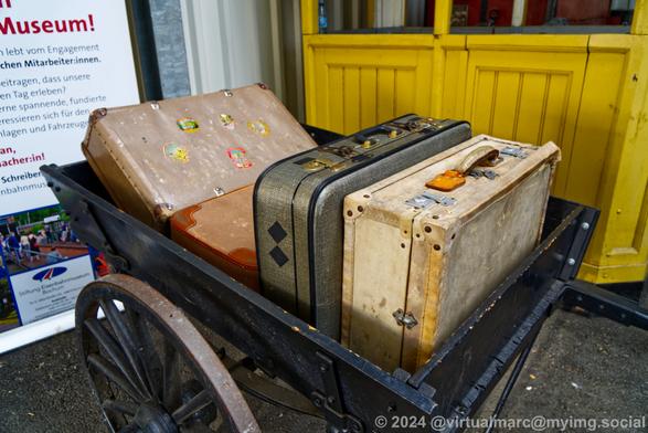 A photo of four luggages inside a wheelbarrow.