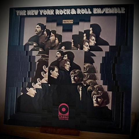 An album cover for "The New York Rock & Roll Ensemble," featuring a collage of stylized images of a group of people in profile. The design includes a mix of faces with varying expressions against a dark background. The label is identifiable at the bottom