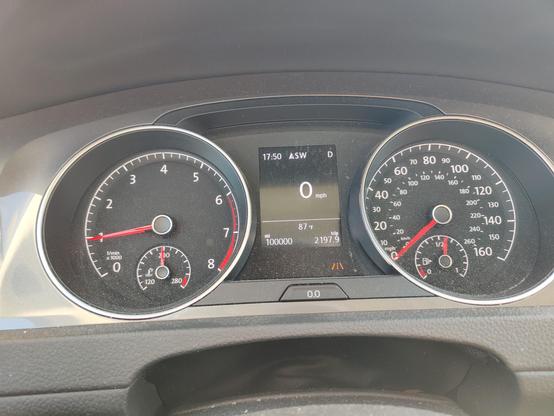 The instrument cluster of a running 2017 VW Golf Alltrack showing 100,000 miles on the odometer.