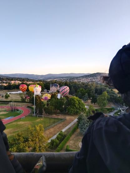 Vue de la nacelle déjà en l'air : champs en contrebas, parc de Deomas avec son château et groupe de montgolfières qui décollent .