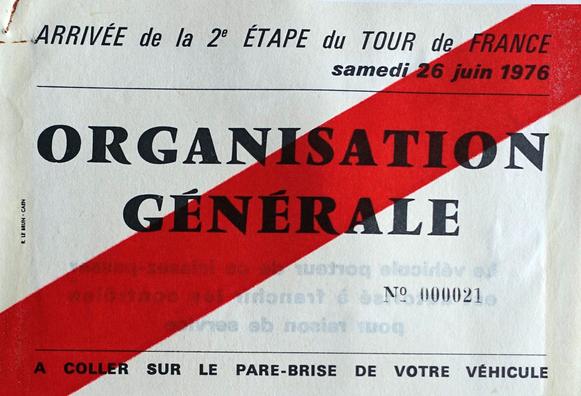 Macaron d'accréditation pour véhicule lors de la 2e étape du Tour de France 1976 (arrivée à Caen) : organisation générale. Papillon blanc barré de rouge, écriture noire