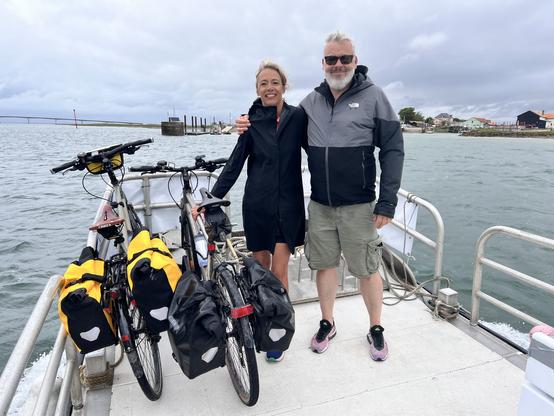 Bénédicte et Tristan, jambes courtes et imperméables, posent sur le bateau avec leurs vélos.