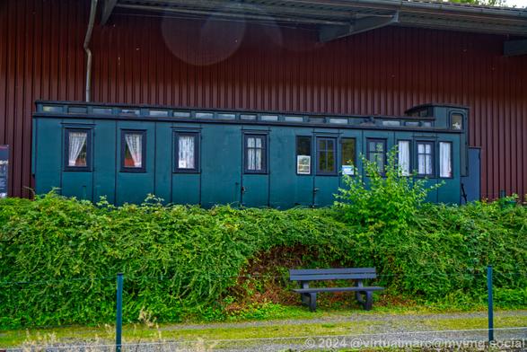 A photo of an old blue passenger car in front of the train car hall 2.