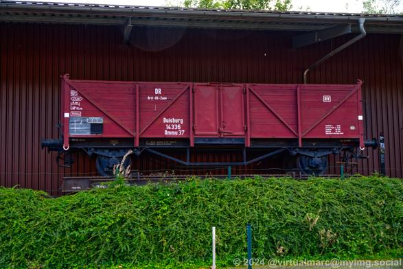 A photo of a red cargo car in front of the train car hall 2.