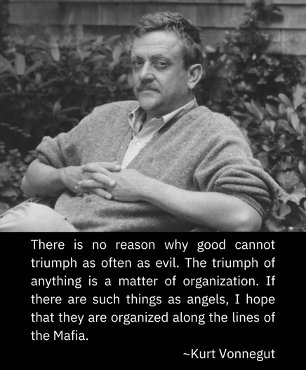The image is a black and white photograph of Kurt Vonnegut sitting outdoors. He is wearing a light-colored cardigan over a collared shirt, with his hands clasped together in his lap. He has a mustache and is looking directly at the camera with a neutral expression. The background consists of blurred foliage, suggesting a garden or park setting.

Below the image, there is a quote attributed to Kurt Vonnegut: "There is no reason why good cannot triumph as often as evil. The triumph of anything is a matter of organization. If there are such things as angels, I hope that they are organized along the lines of the Mafia." The quote is presented in white text on a black background, contrasting with the grayscale image above.