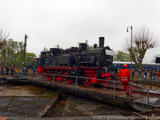 A photo of a steam locomotive on the turntable. It has the number 74 1192. A sign at the front says: Berlin Görlitz Bahnhof.