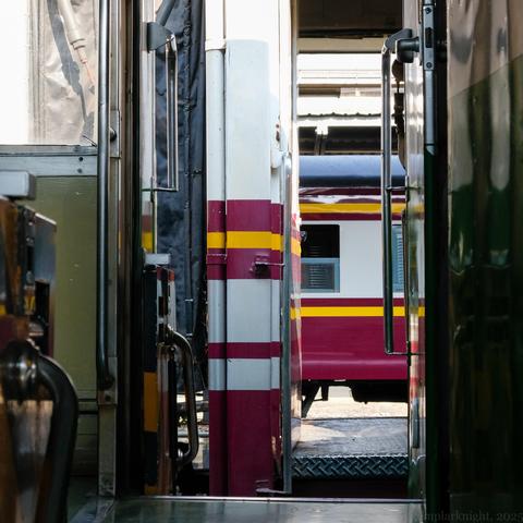 color photo of several parked stationary passenger trains viewing from the gap between the compartments