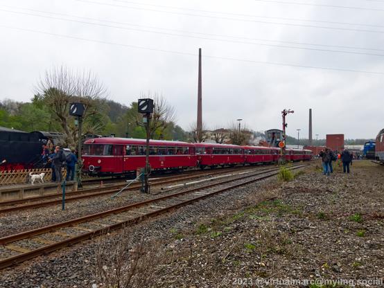 A photo of a red railway bus with 6 wagons entering the train station.