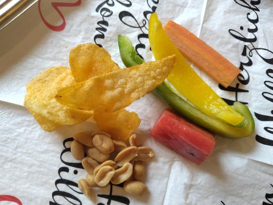 Vegane Schlemmerei: Paprika, Möhre, Wassermelone, Chips und Erdnüssli; auf einer Papierserviette.