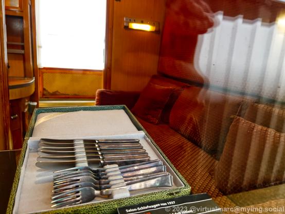 A photo of the inside of a sleeping car from 1937, which was used by Adolf Hitler, through a window. Forks and Knifes are lying on the table.