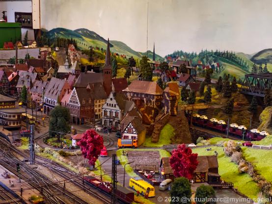 A photo of a model railway with a small town with some half timbered houses and a church. It also has a tram line.