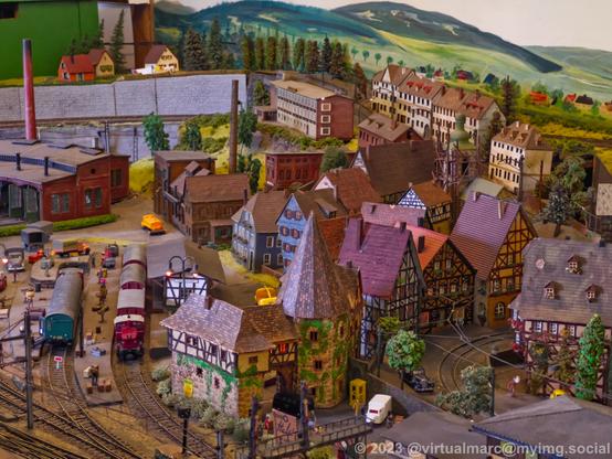 A photo of a model railway with an old city with half-timbered houses and a small castle. There is a railway depot in the back.