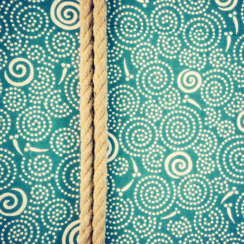 An aqua green-blue Japanese facecloth depicting swirls (probably where raindrops are landing on the water?) and slightly abstract fish swimming in pairs.