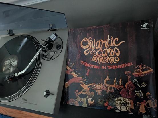LP playing on turntable next to record jacket
