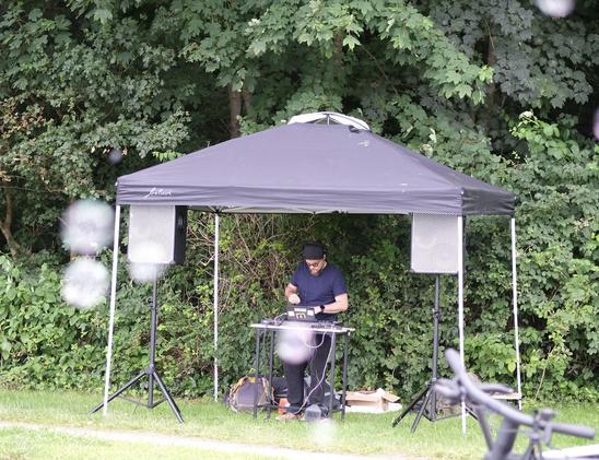 Ein DJ unter einem Zeltdach. Im Vordergrund fliegen Seifenblasen durchs Bild.