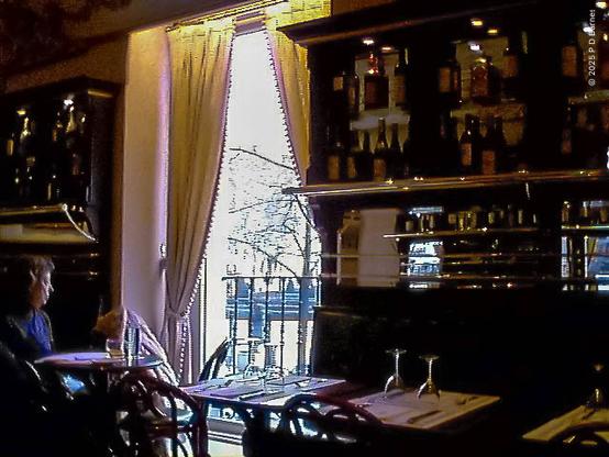 The interior of a café / bar with bottles and glasses lining the walls, tables set for dining, and a window showing an overexposed park outside. Clearly I couldn't afford to drink there 😄