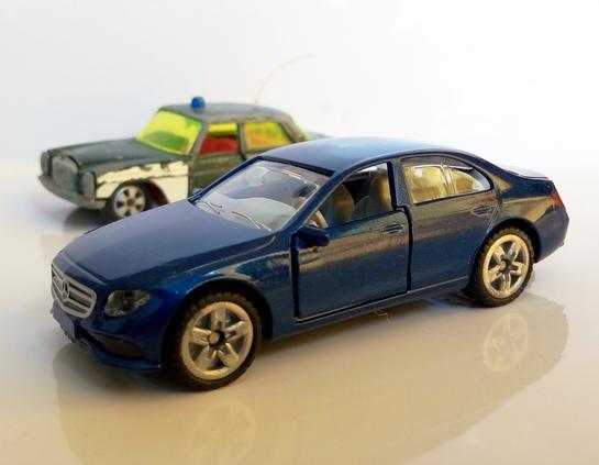 Two model cars: Siku Mercedes-Benz 250 police car in background and a blue Siki Mercedes-Benz E350d in foreground.