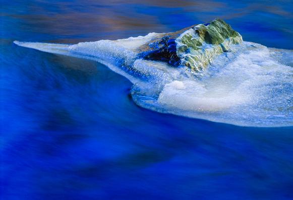 Ice forming around a rock in the middle of a small river north of Montreal in early winter.