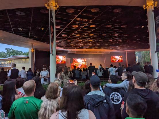 The amphitheater stage with people crowded around it while Kygo plays on stage with visuals on three different TVs.