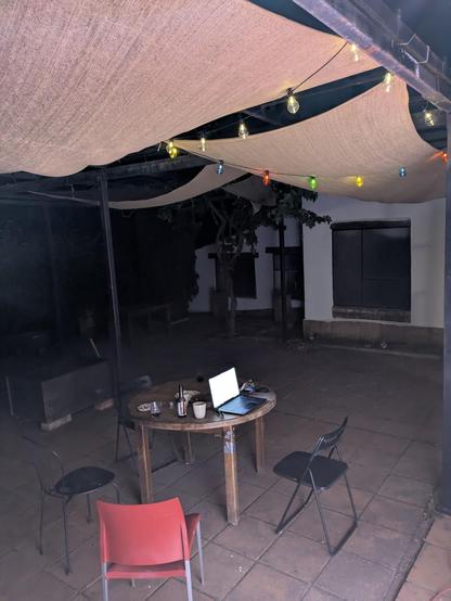 A patio somewhere in Spain at night. There is some indirect lighting, a chain of solar decorative lights and a gimp maintainers laptop on a table.