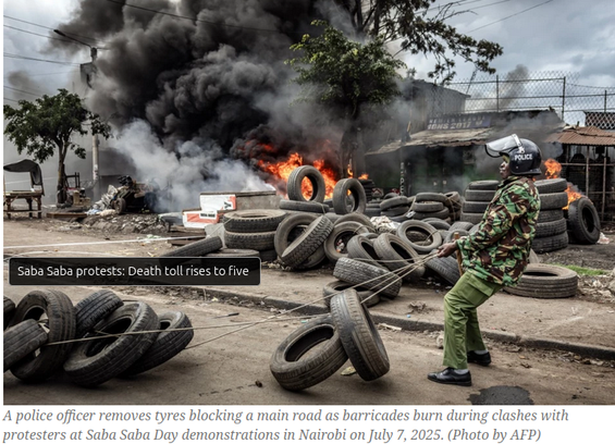 A police officer removes tyres blocking a main road as barricades burn during clashes with protesters at Saba Saba Day demonstrations in Nairobi on July 7, 2025. (Photo by AFP)