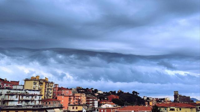 Foto panoramica di Lerici. In basso gli edifici, case colorate. In fondo a destra si vede il castello. Il cielo è nuovoloso, con nuvole molto scure e forme ondeggianti molto minacciose
