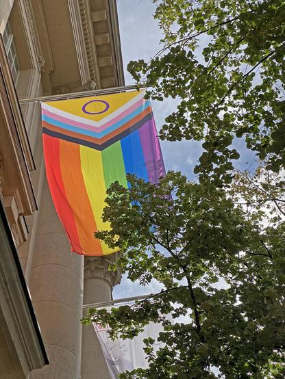 Das Bild zeigt eine Regenbogen-Pride-Flagge, die vor dem Haus Unter den Linden der Stabi Berlin gehisst wurde.