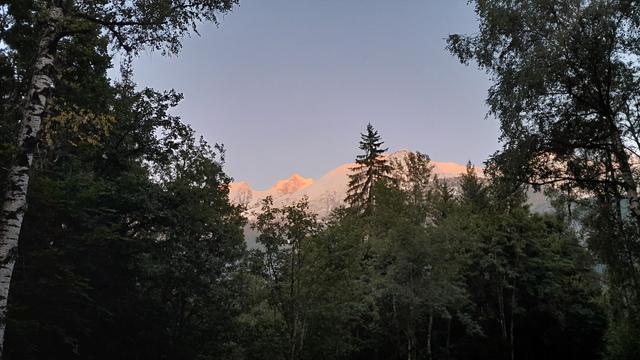 Schneebedeckte Berge vom Sonnenuntergang Orange angeleuchtet.