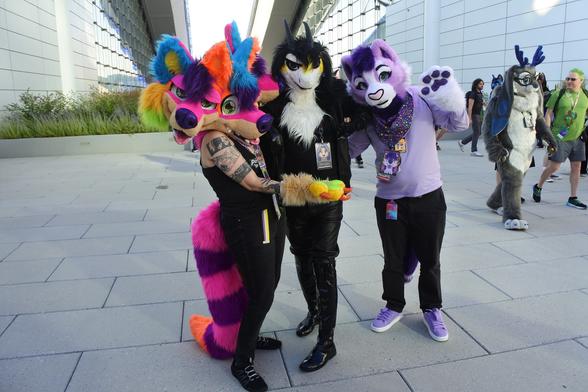 Three fursuiters on top of the DLCC building at Anthrocon in Pittsburgh.
Left is a three-headed rainbow dog, middle is a white furred dragon in a leather jacket.  Right is a lavender cat

This photo was taken by a bystander using my camera