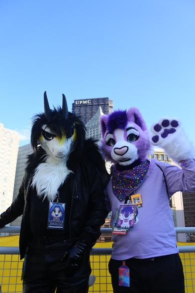 A dragon fursuiter and a lavender cat on the roof of the DLCC building