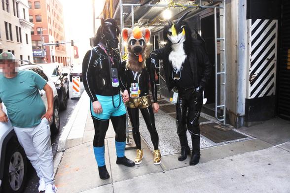 Photo of some rubber-clad fursuiters we met on the way back from the Dragon Meet at Anthrocon.  On the left is a pony in a black latex catsuit with turquoise boxers, whose name I can't make out on the badge.  In the middle is a hyena-looking creature called Sunny, in a black latex catsuit but with gold briefs and shoes. On the right, in PVC jeans and gloves, is Terry the dragon.

Photo taken by Merlin