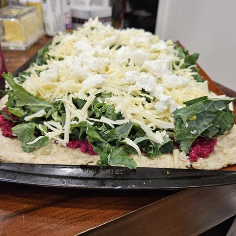 My beet pesto, kale, goat cheese pizza, pre baking. It has a purple sauce on the bottom, and then is piled high with kale, which will bake down, and then on top of the kale is mozza and a small amount of goat cheese. It looks more salad than pizza, but I've made it before and I know it'll be tasty.