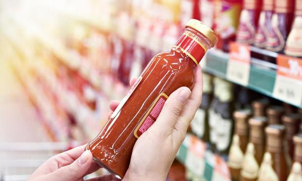 Una mujer con un bote de salsa en el supermercado (Getty Images/iStockphoto)