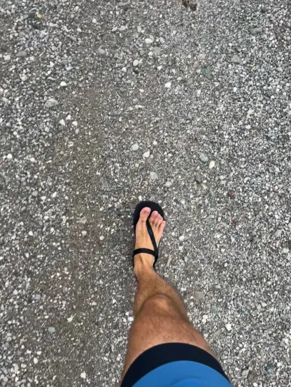 Ein Bein im Lauf, oben blaue Shorts, unten schwarze Sandale.