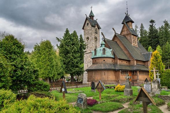 Im Vordergrund der Friedhof vor der Kirche. Dahinter die Stabkirche und dahinter der Wald.