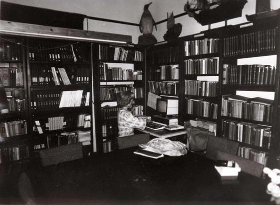 historisches Foto: eine Person sitzt an einem Computer (ca. Ende der 1980er-Jahre oder Anfang der 1990er Jahre), dahinter hohe Bücherregale, Copyright by IGB Berlin. Zu finden im Buch "Auf den historischen Spuren des IGB: Ein Jahrhundert Forschung an Gewässern". zugänglich unter https://www.igb-berlin.de/institutsgeschichte