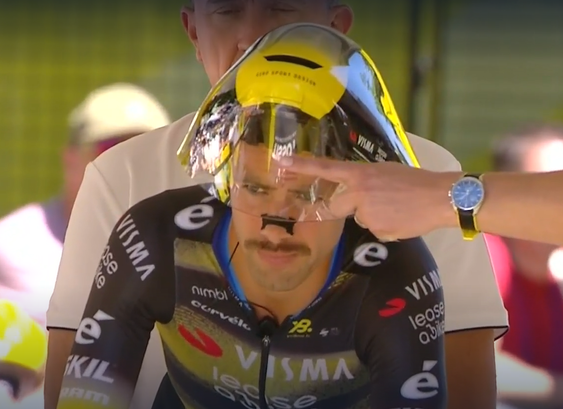 Radfahrer vor dem Start beim Zeitfahren der Tour de France mit einem Schnauzbart und einem schwarzen Nasenpflaster